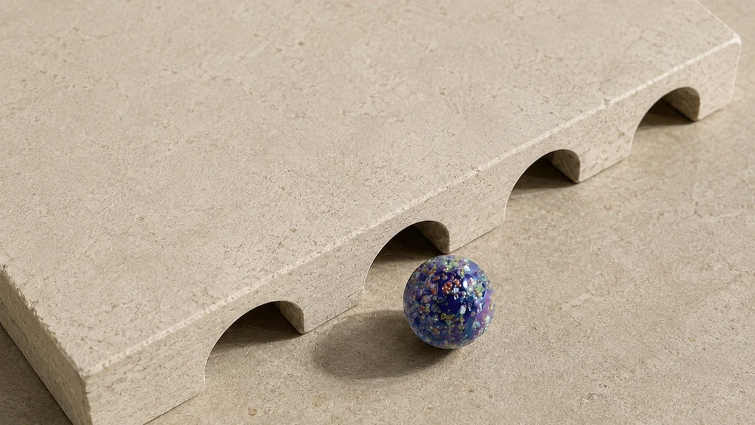 Une planche de bois percée d'arcades en demi-cercle, posée à plat, avec une bille de verre arrêtée devant l'une des ouvertures.