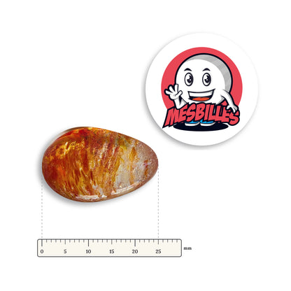 Bille Oeuf Cristal Moucheté Orange et Rouge couchée à côté d'une règle graduée, environ 25 mm de long