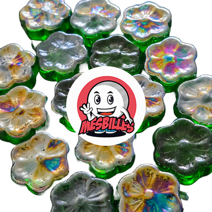 Vista ravvicinata di diverse biglie piatte Fleur Cosmos verdi e iridescenti, in vetro, disposte attorno al logo MieiBiglie.